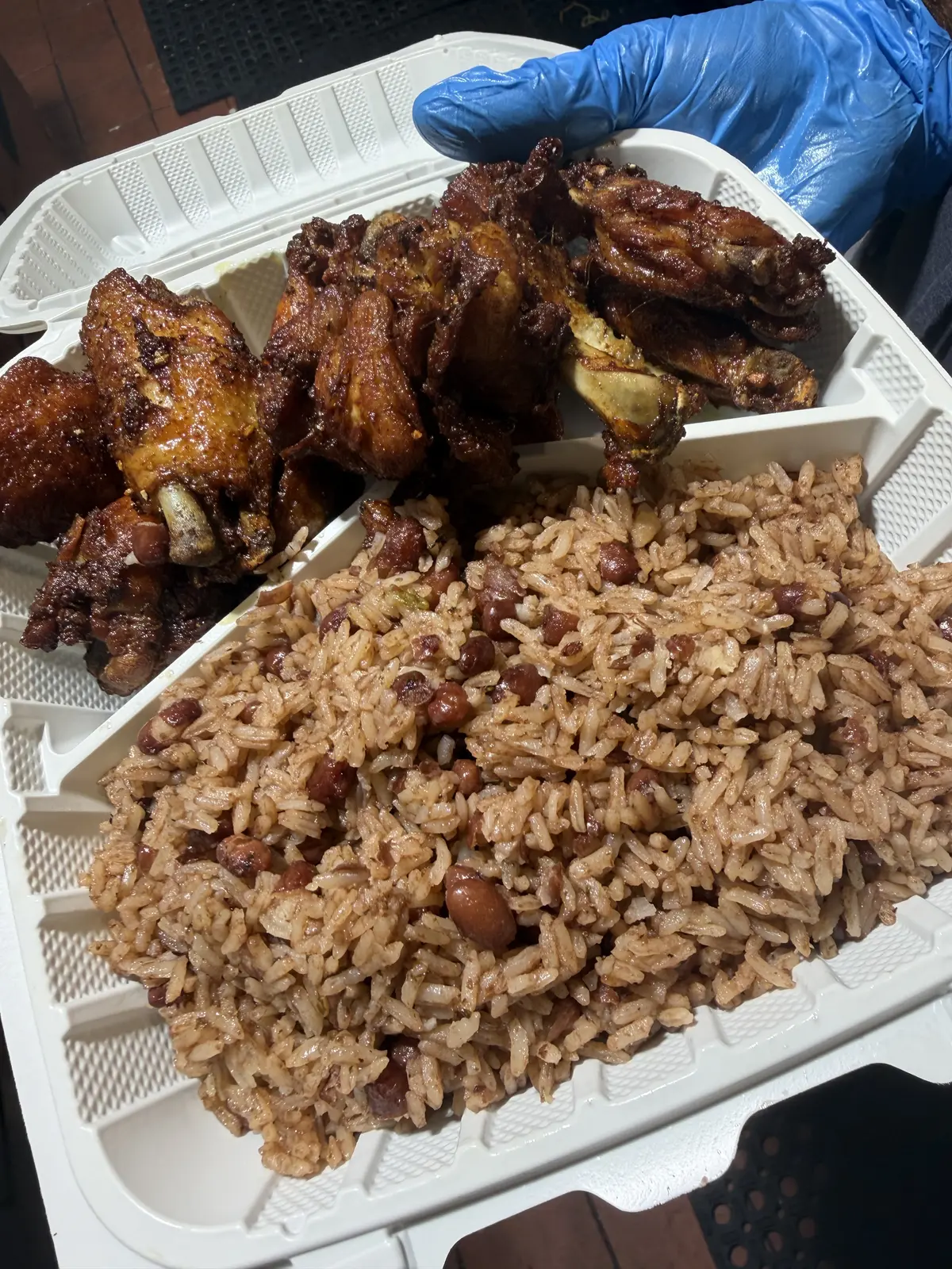 A platter of seasoned fried chicken wings with Caribbean rice and peas from Dinner Is Served