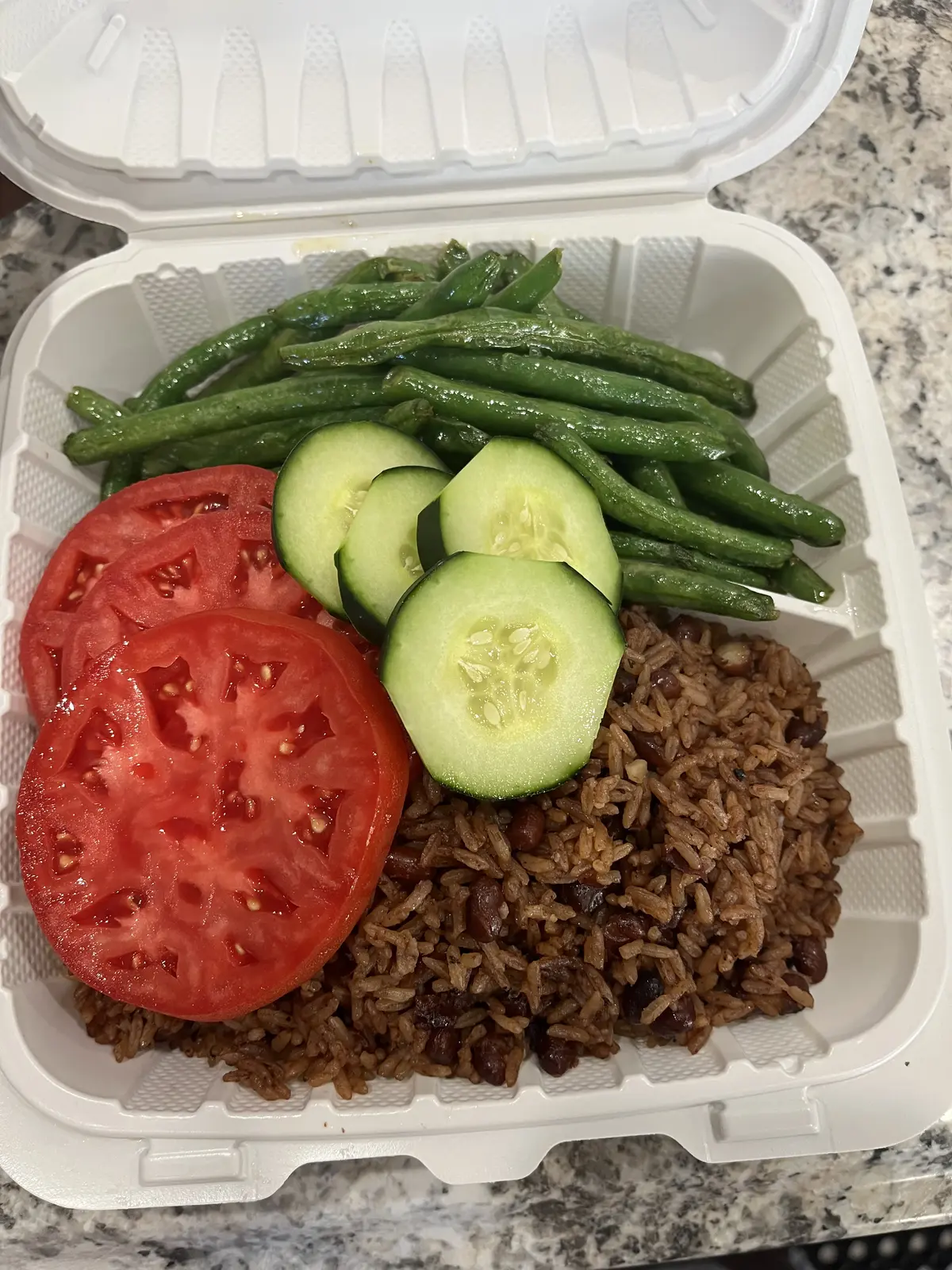 A takeout plate of Caribbean rice and peas with green beans, tomato, and cucumber from Dinner Is Served in Miami Shores