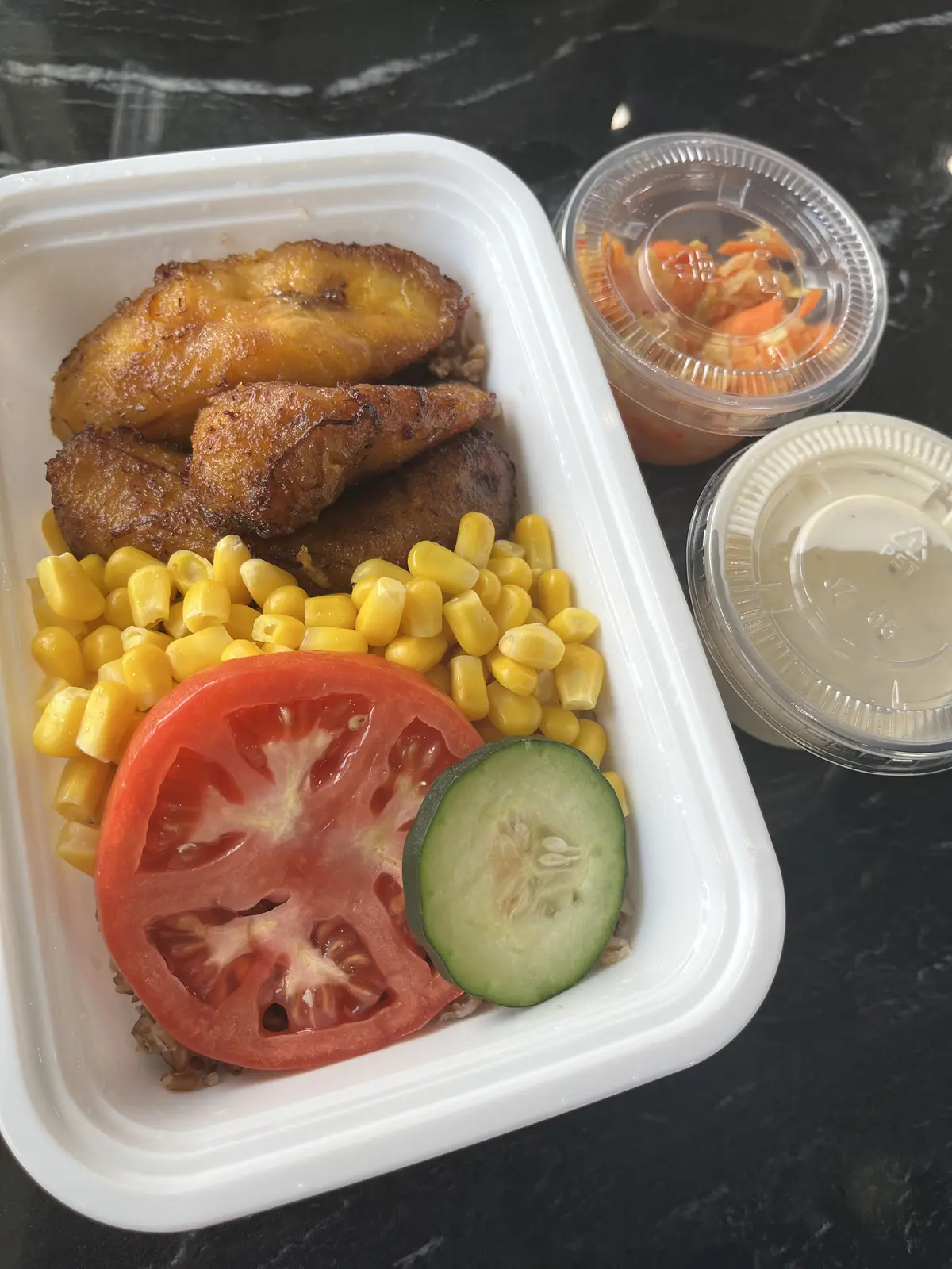 A fresh takeout order of sweet plantains, corn, and salad with sauce cups from Dinner Is Served in Miami
