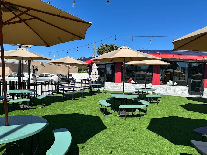 The outdoor patio at Dinner Is Served in Miami, with shaded picnic tables and string lights